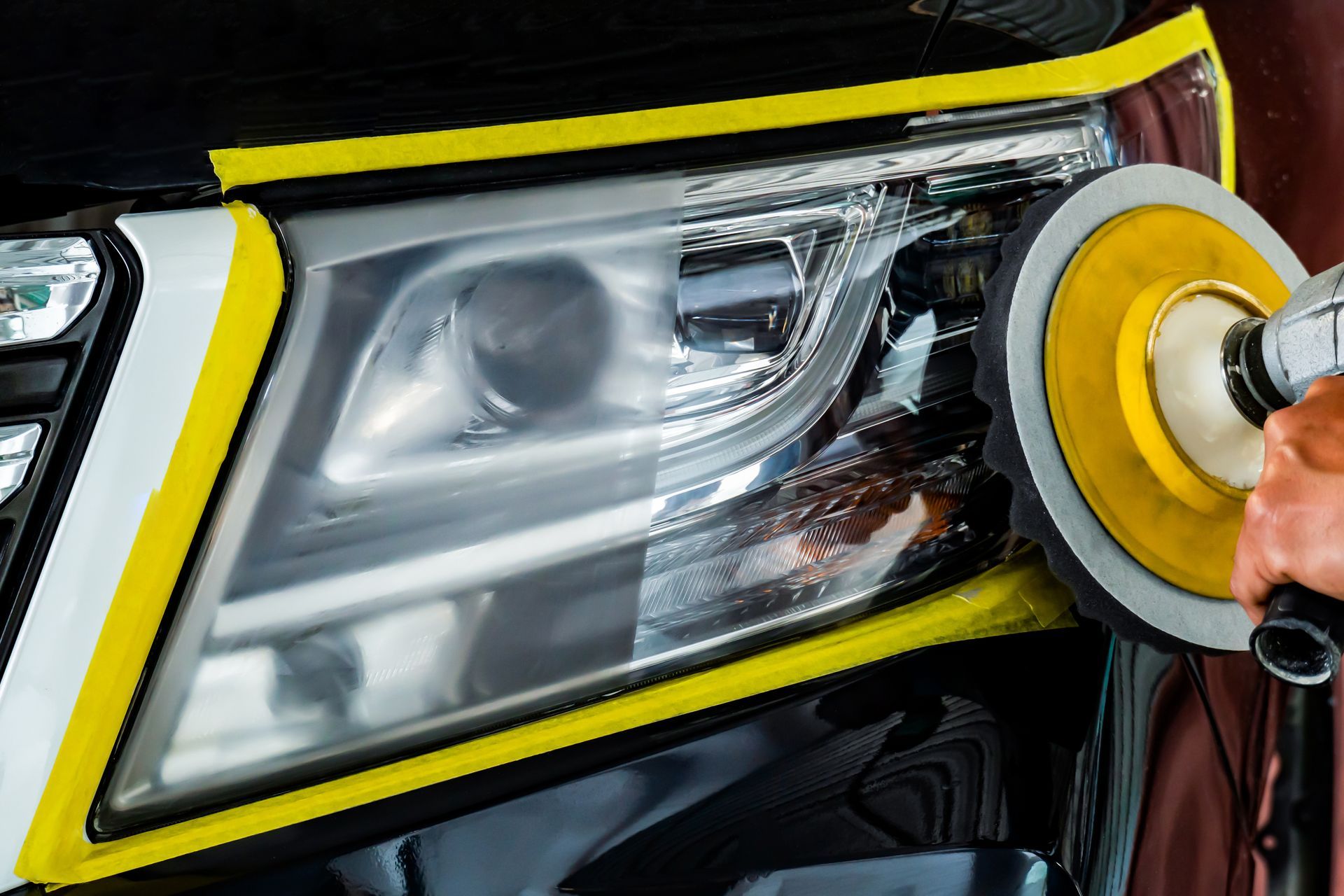 A person is polishing the headlights of a car.