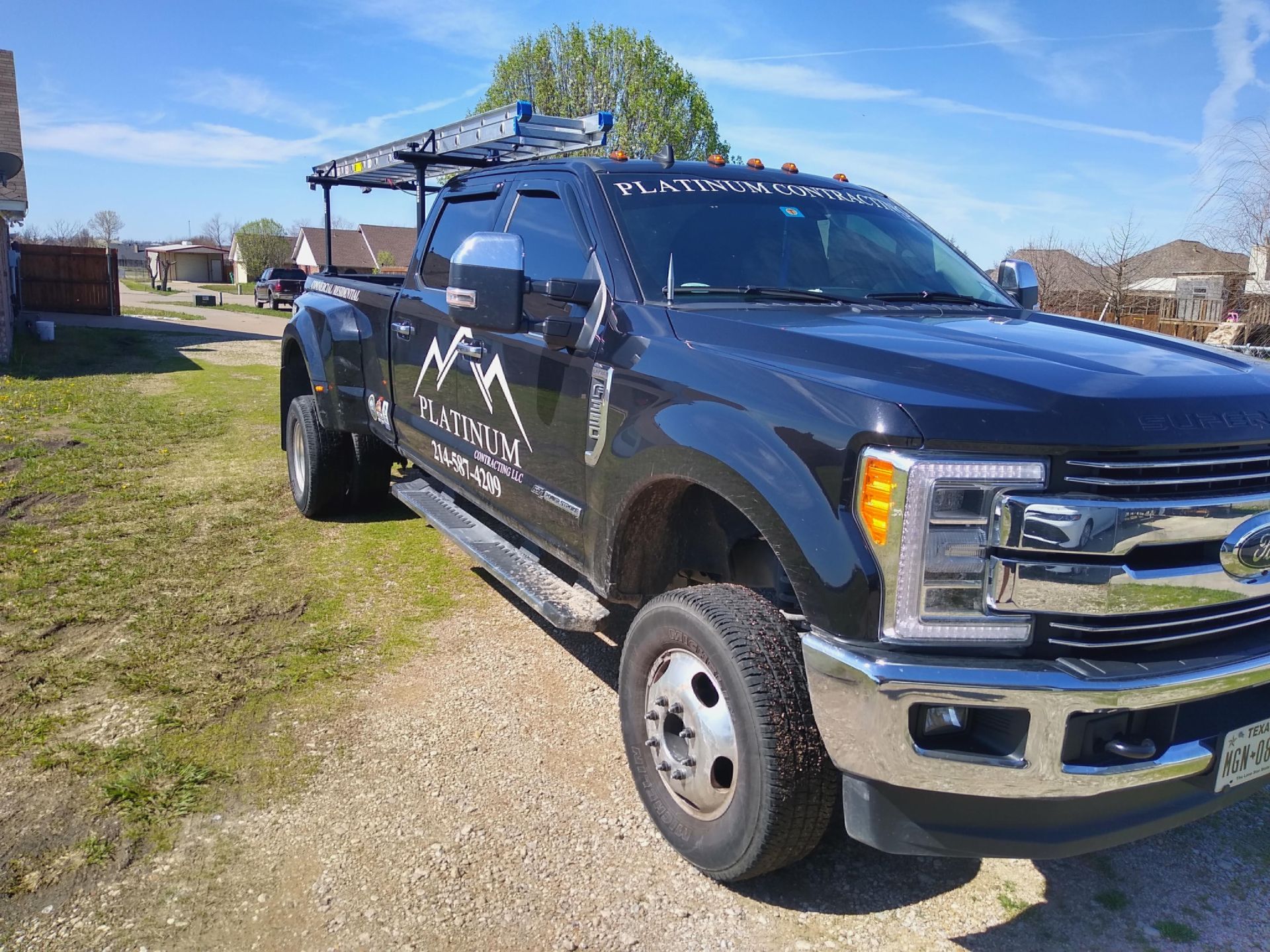 Black Ford truck with ladder rack parked outside, company logo visible.