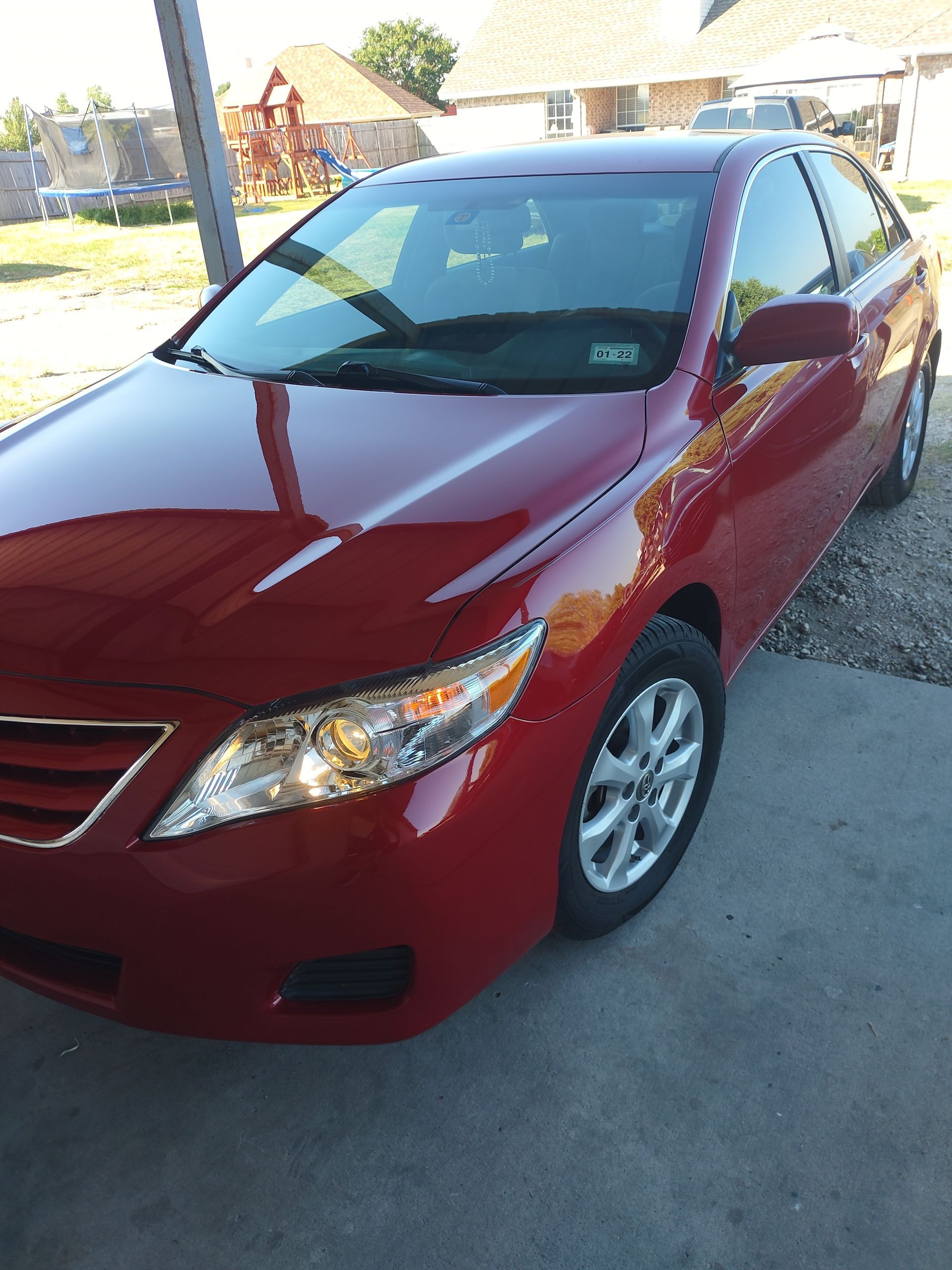 Red Toyota Camry parked on a concrete driveway.