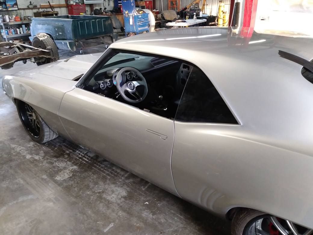Silver classic car in a garage with black wheels and interior.