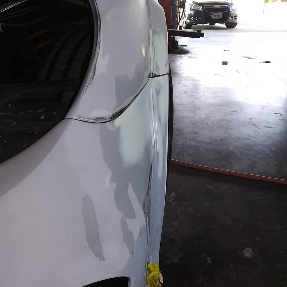 White car fender being repaired at an auto shop.