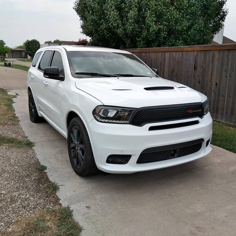 White Dodge Durango SUV parked on a driveway with a black grill and wheels.