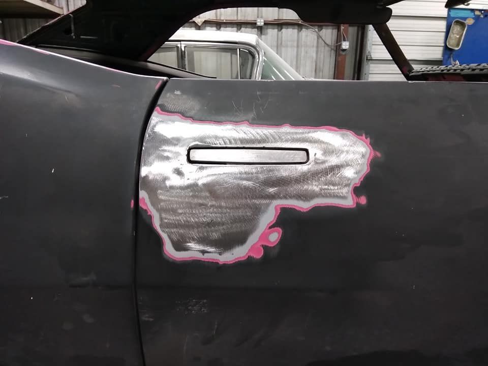 Car door with exposed metal around a handle, primed for bodywork.