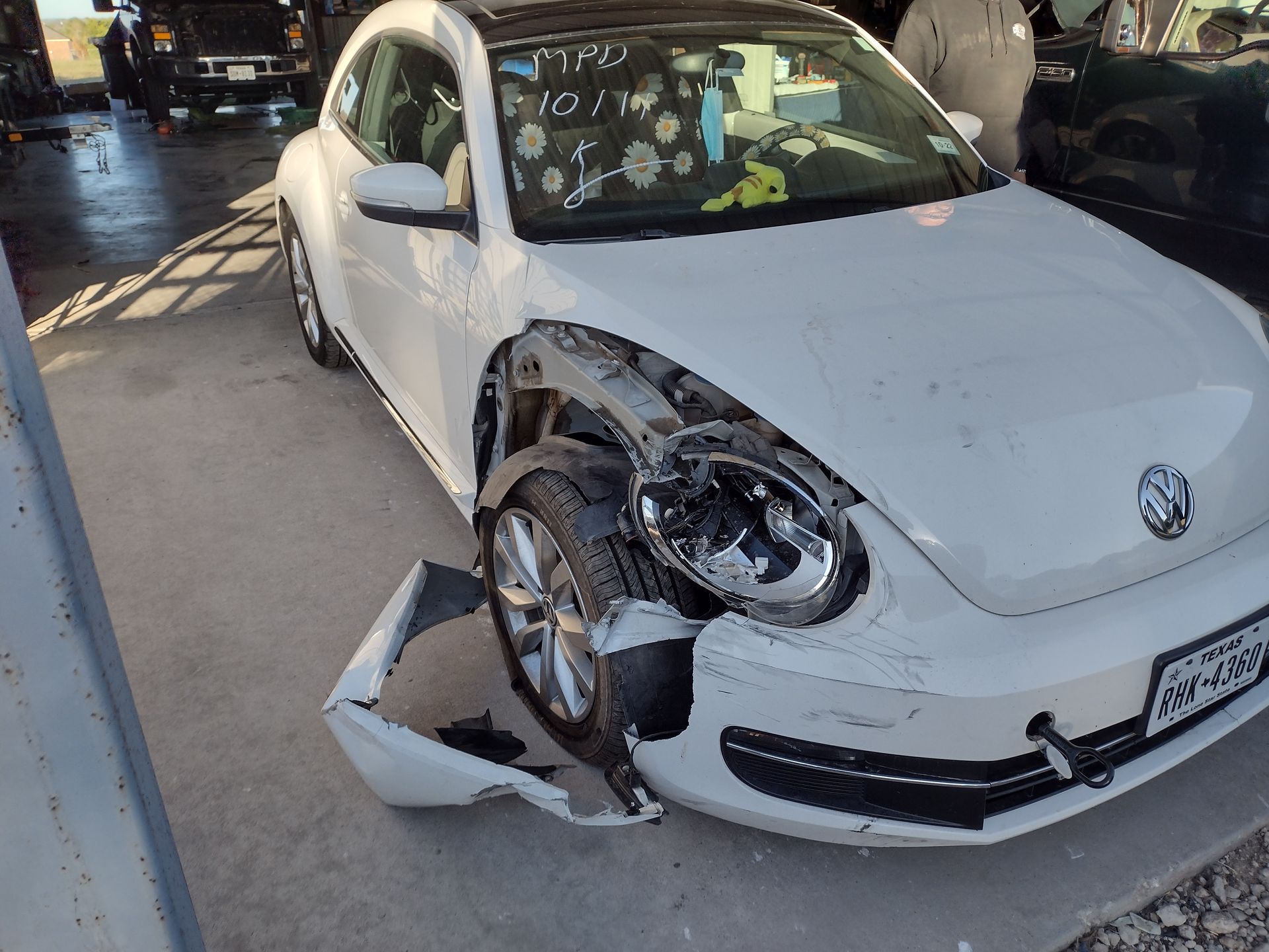 White VW Beetle with front-end damage; headlight and fender detached.