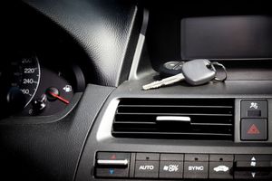 Car dashboard with keys, showing a speedometer, vents, and buttons.
