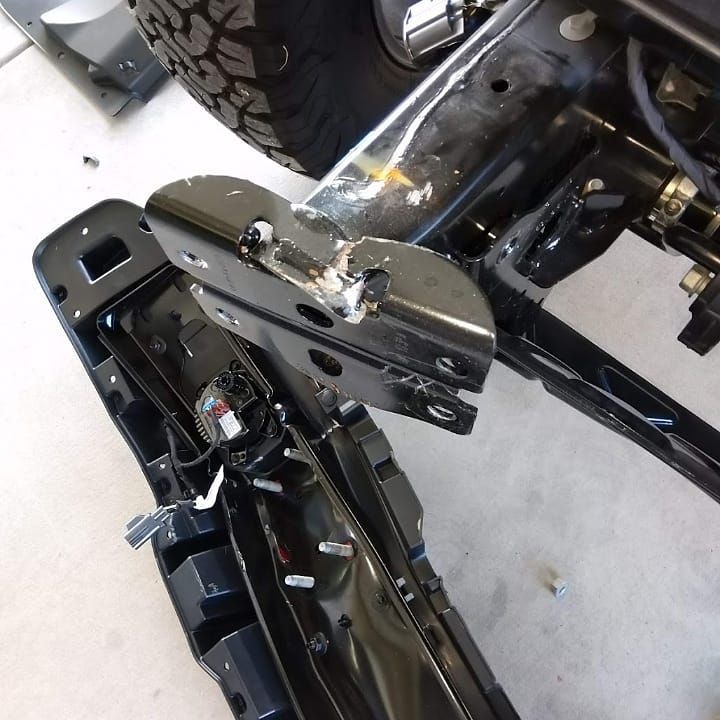 Damaged black vehicle bumper and bracket, detached from the frame.