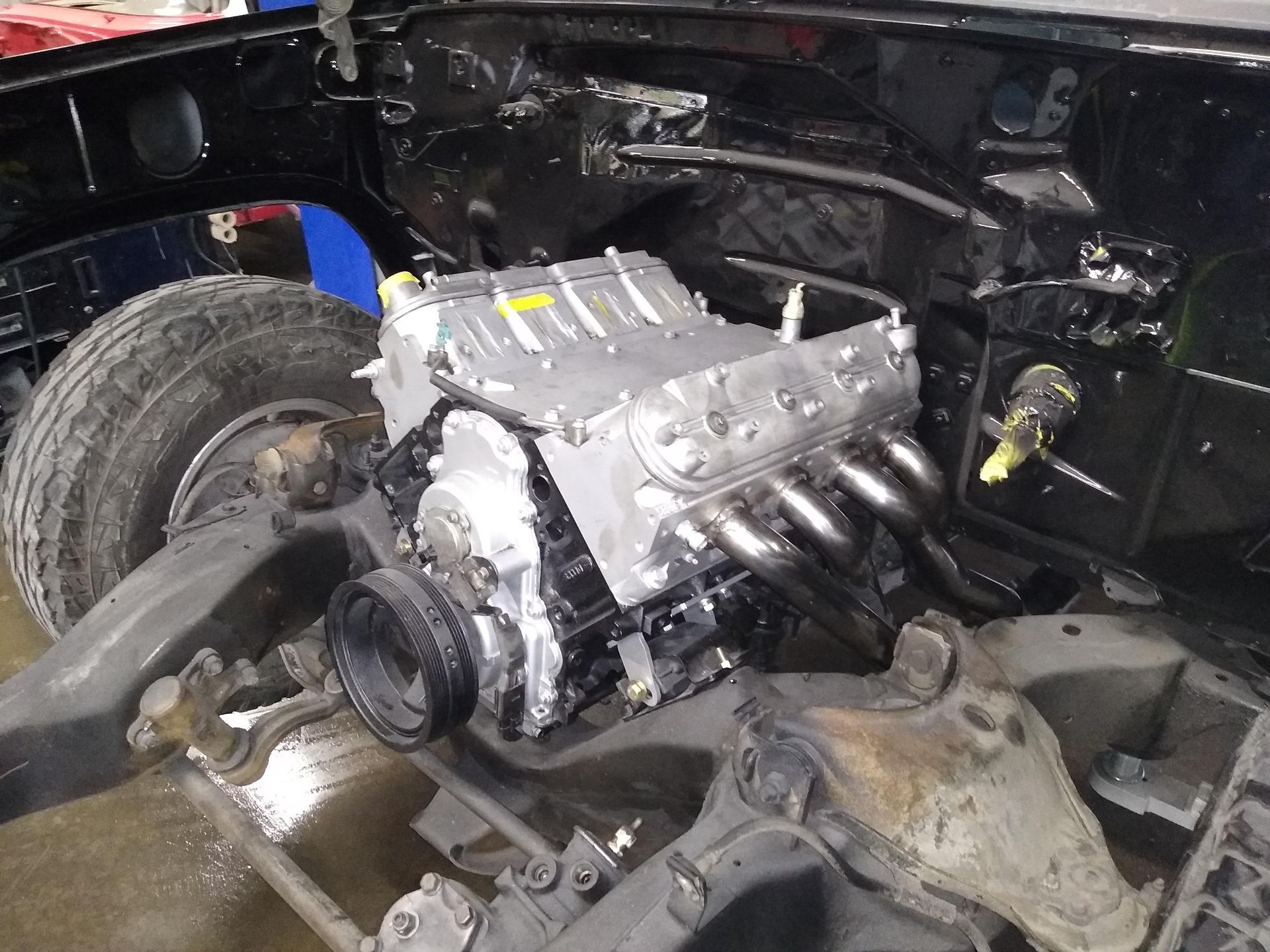 LS engine installed in a car chassis, viewed from the front, with black painted body components.