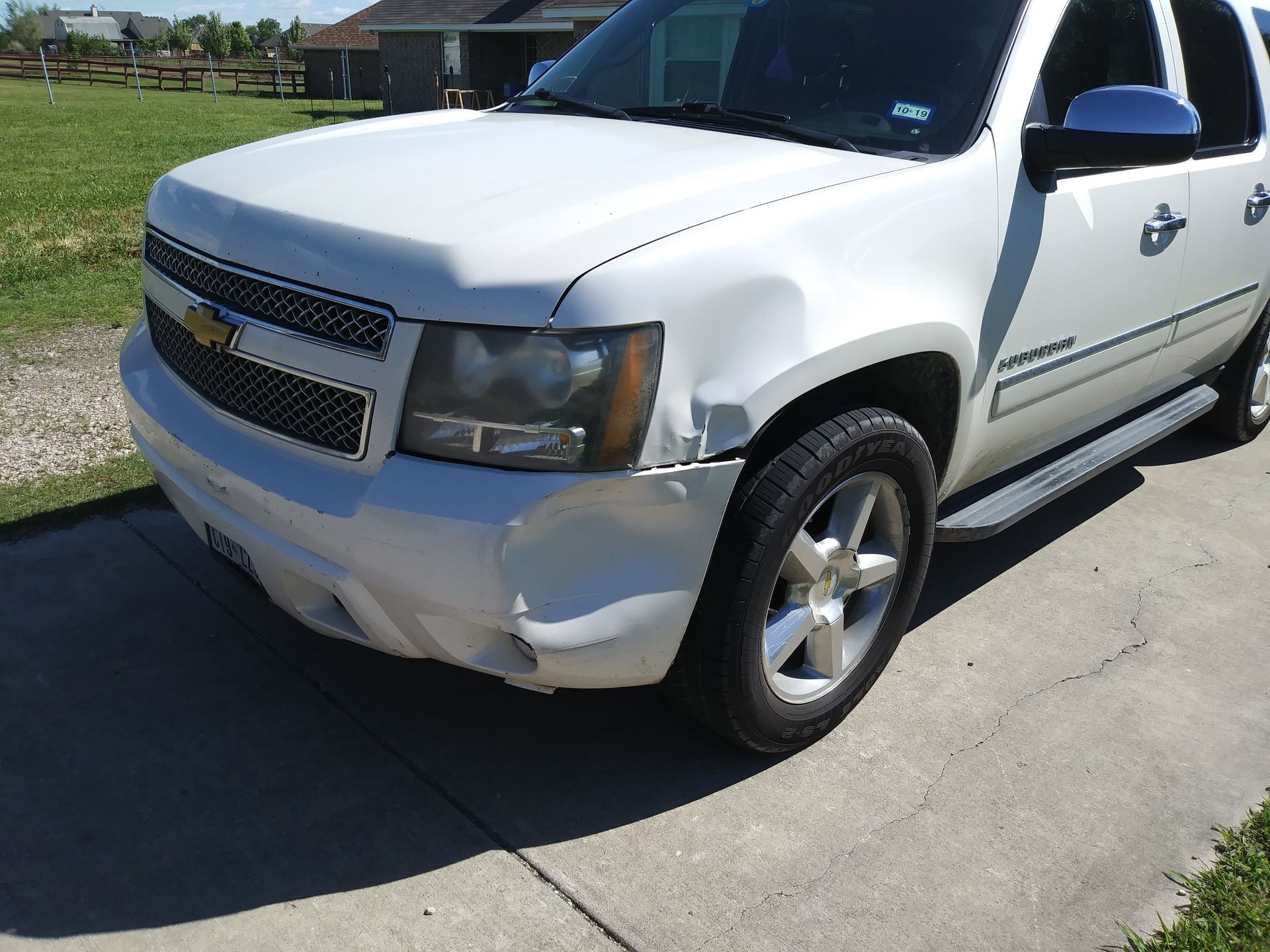 White Chevrolet SUV with front-end damage, parked on a driveway.