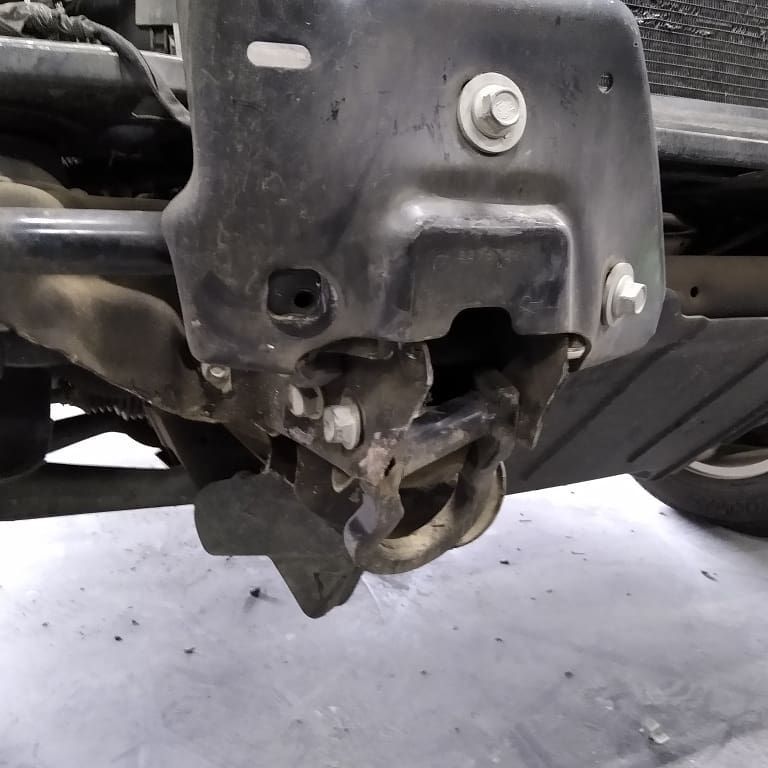 Close-up of a damaged black car bumper with exposed metal and tow hook.