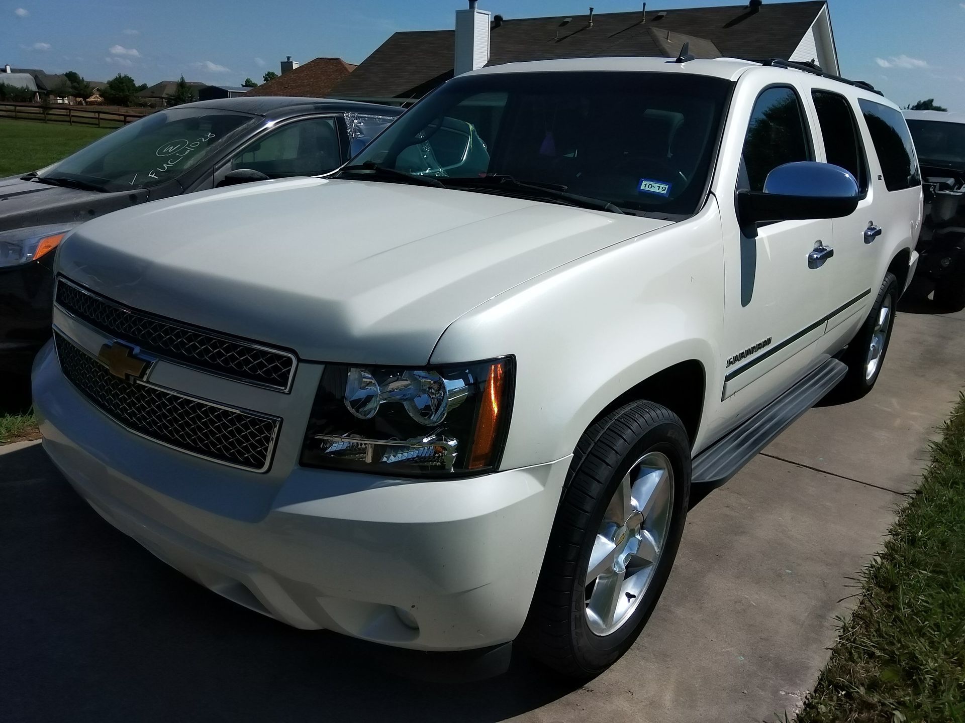 White Chevrolet Tahoe parked on a driveway on a sunny day.