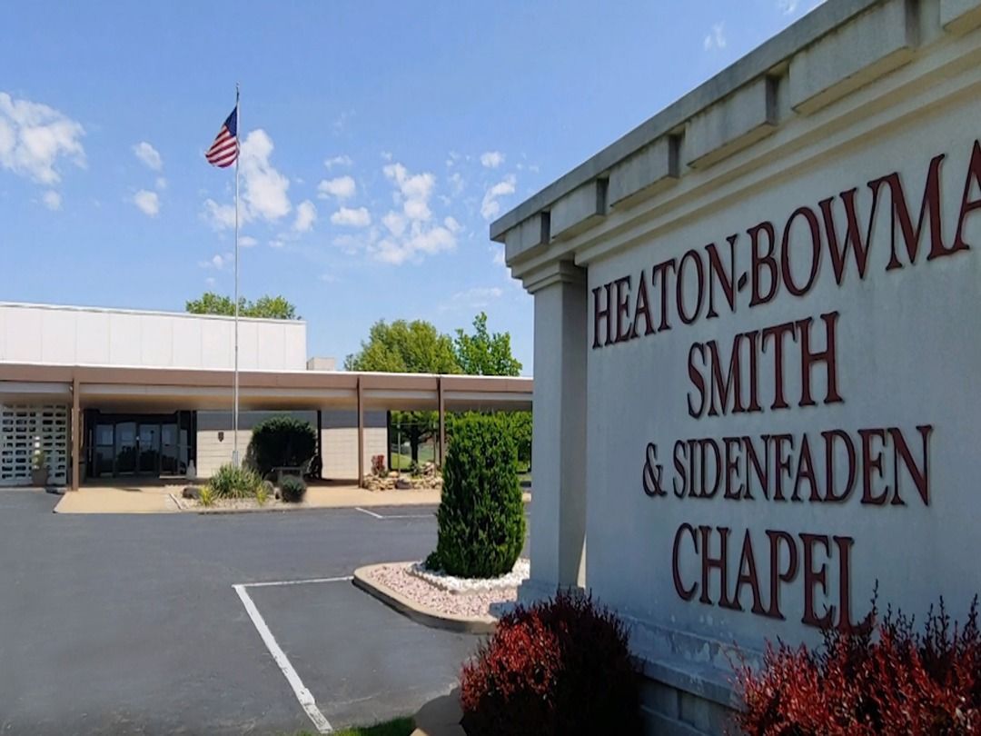 Heaton-Bowman-Smith & Sidenfaden Chapel sign beside a parking lot and building under a blue sky