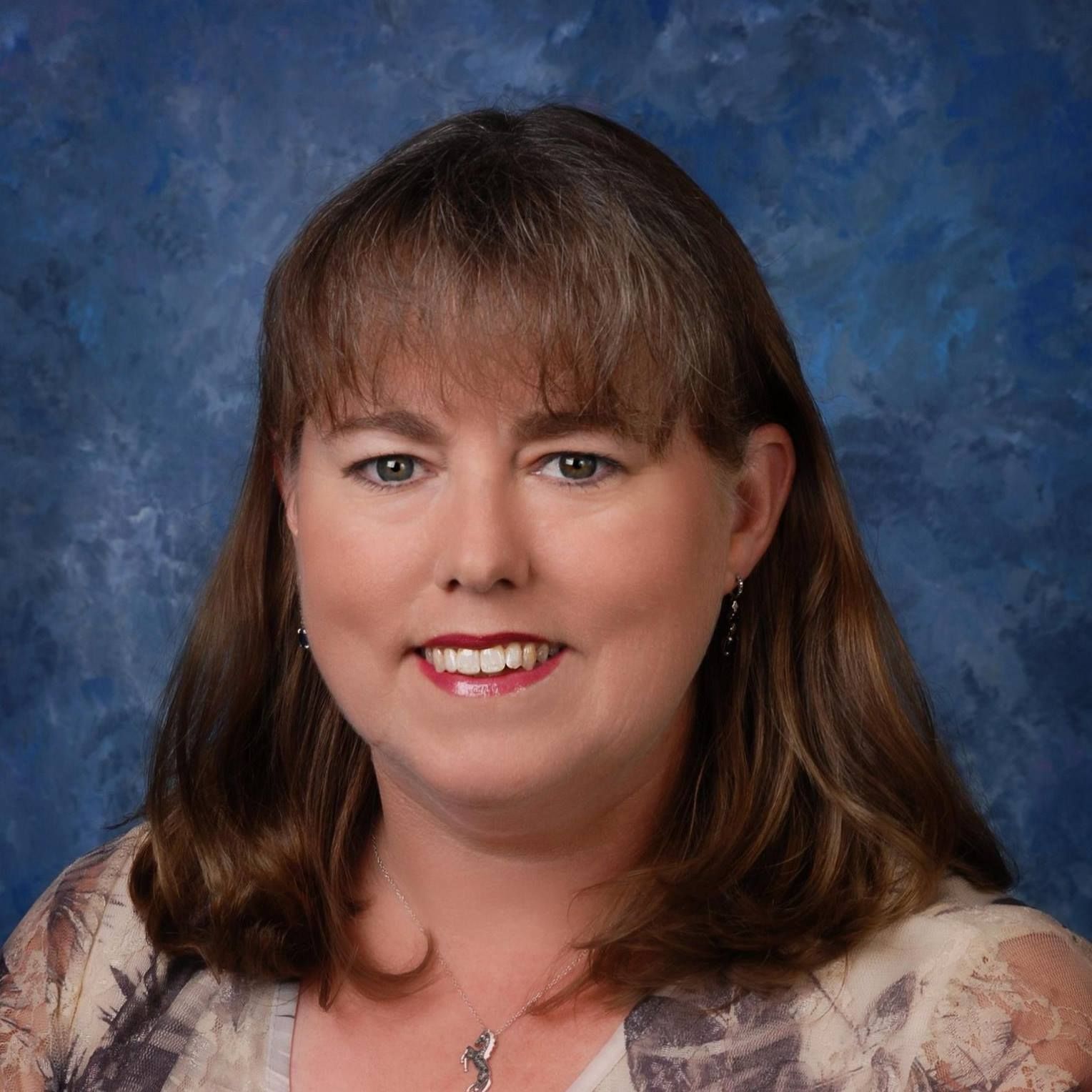 A woman is smiling for the camera in front of a blue background