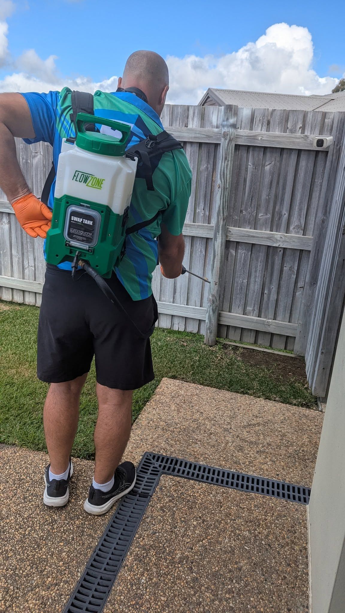 Person Spraying a Backyard Fence with Backpack Sprayer — Total Pest and Carpet Cleaning in Yeppoon, QLD