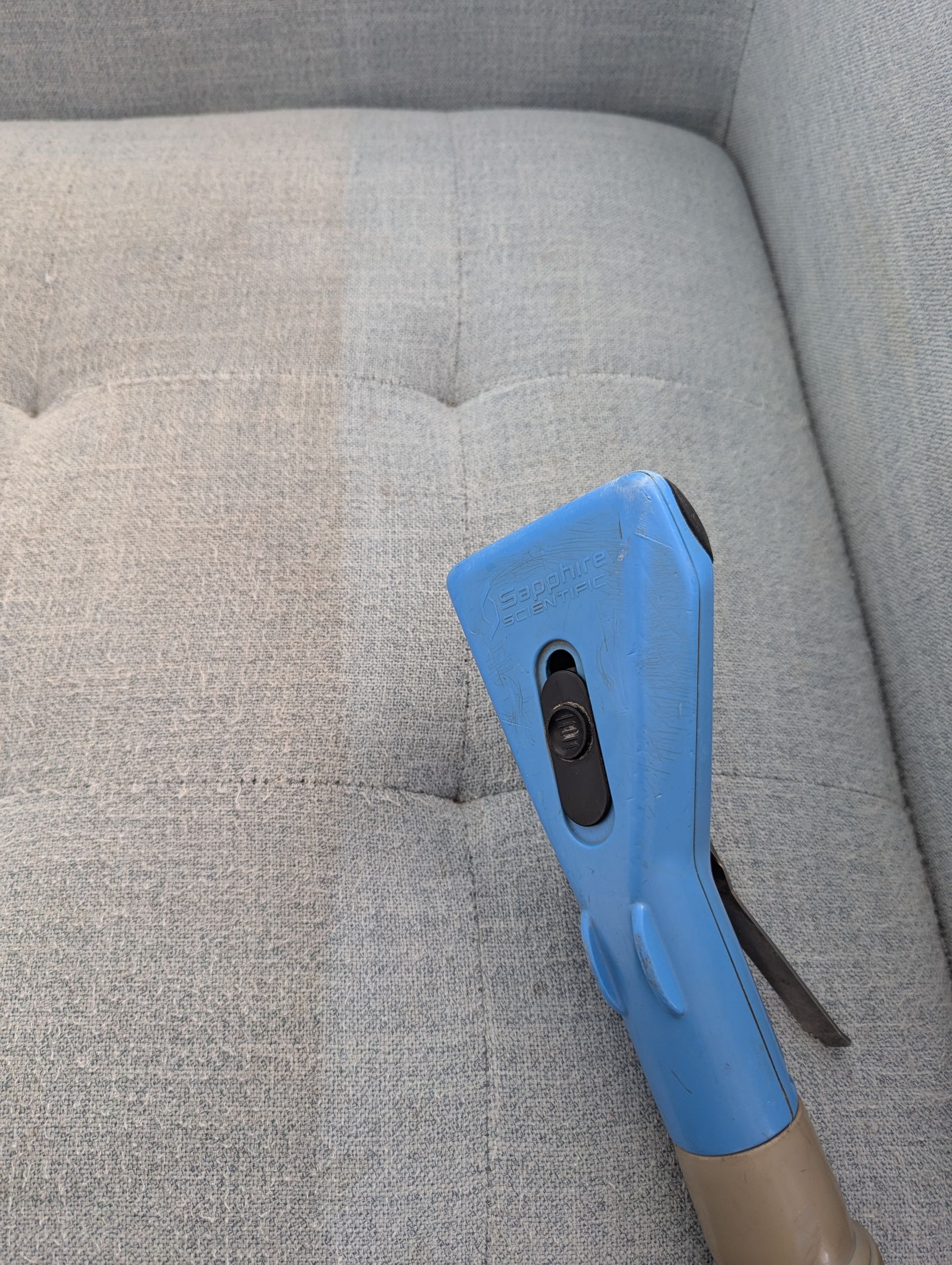 A Person is Spraying a Couch With a Sprayer in a Living Room — Total Pest and Carpet Cleaning in Yeppoon, QLD