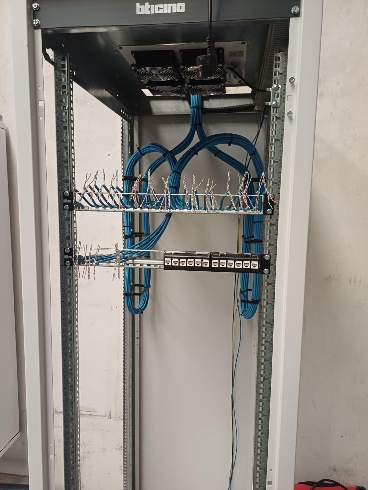 Armadio server di rete aperto con cavi Ethernet blu e pannelli di permutazione ordinatamente instradati all'interno