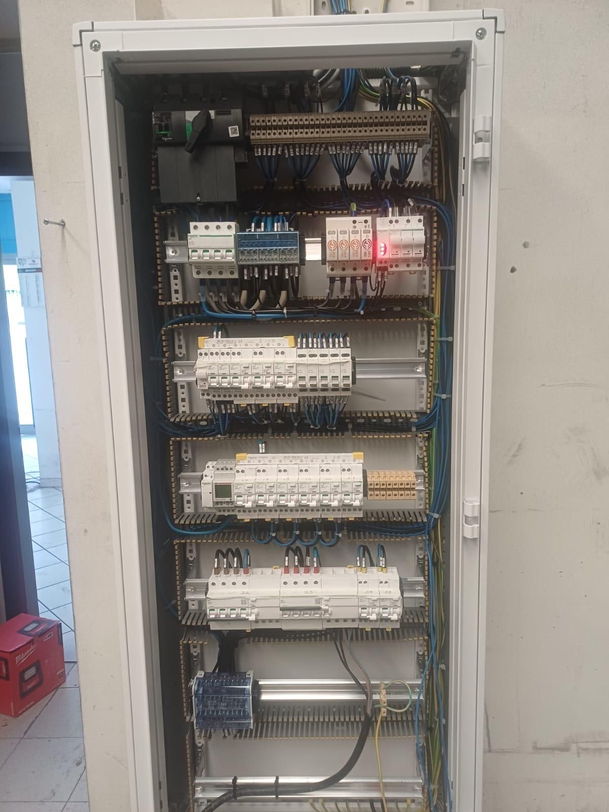 Quadro elettrico aperto con file di interruttori, relè e cavi.