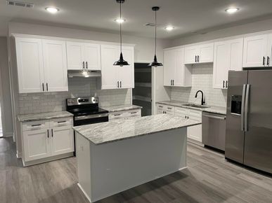 A kitchen with white cabinets , granite counter tops , stainless steel appliances and a large island.