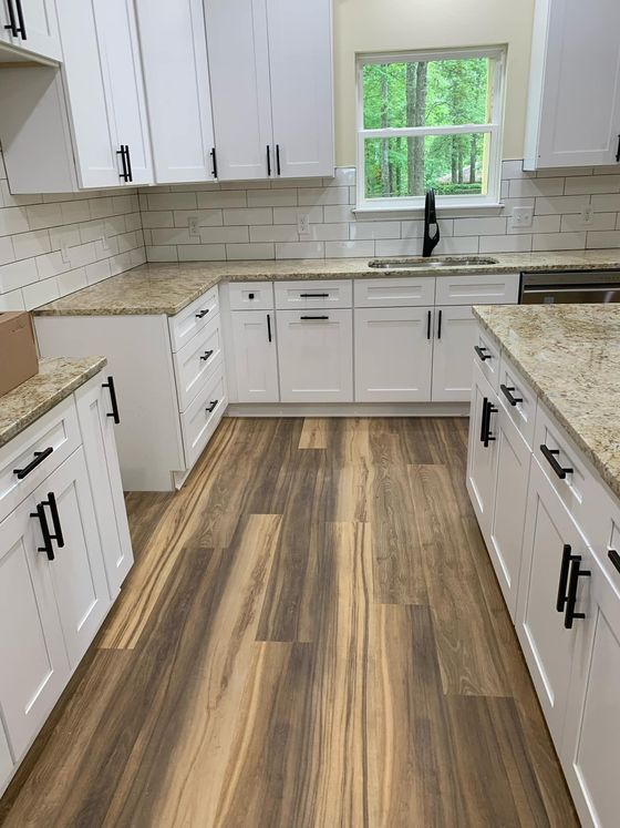 A kitchen with white cabinets , granite counter tops , and hardwood floors.