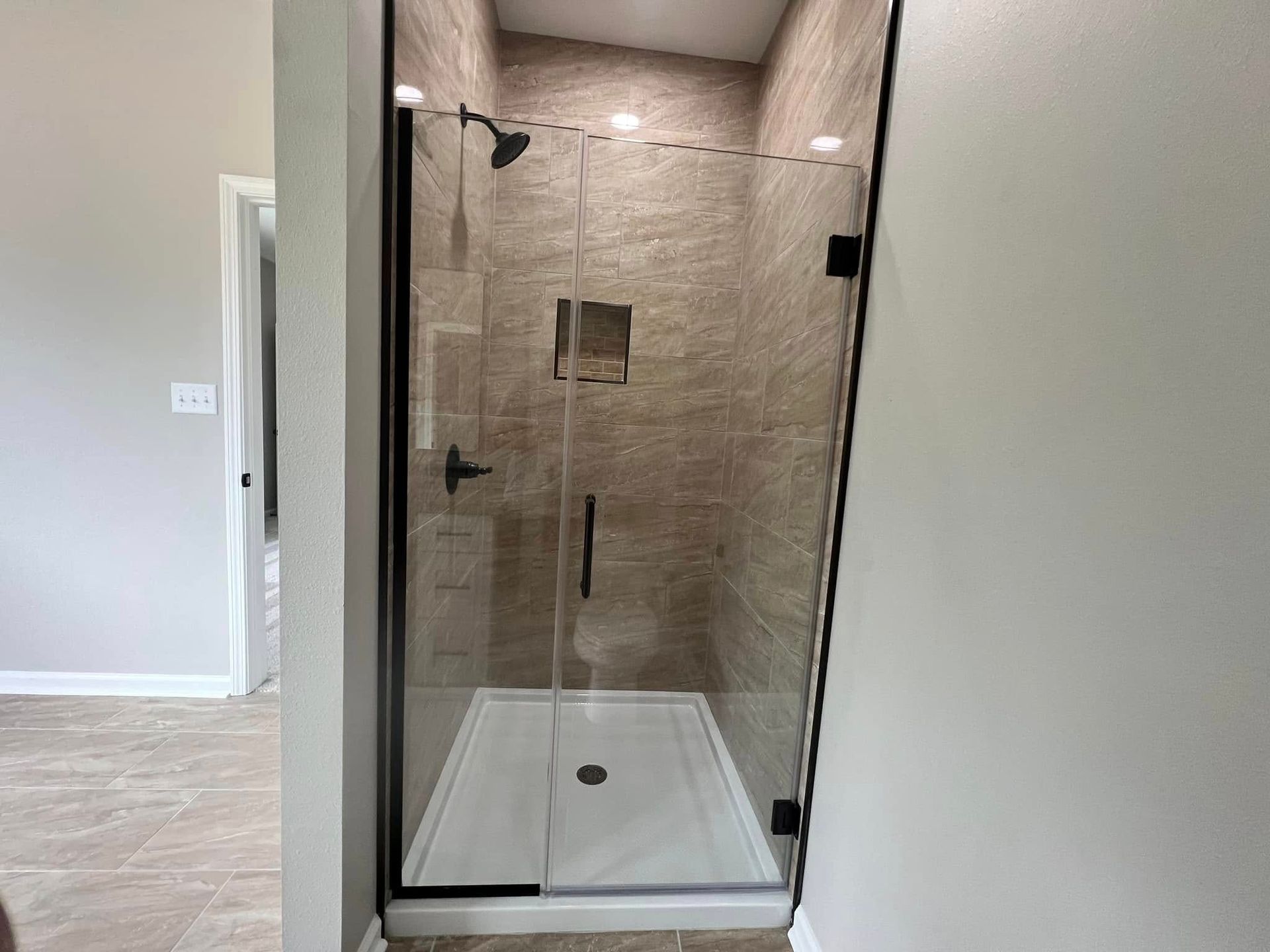 A bathroom with a walk in shower with a glass door.
