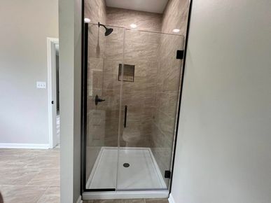 A bathroom with a walk in shower with a glass door.