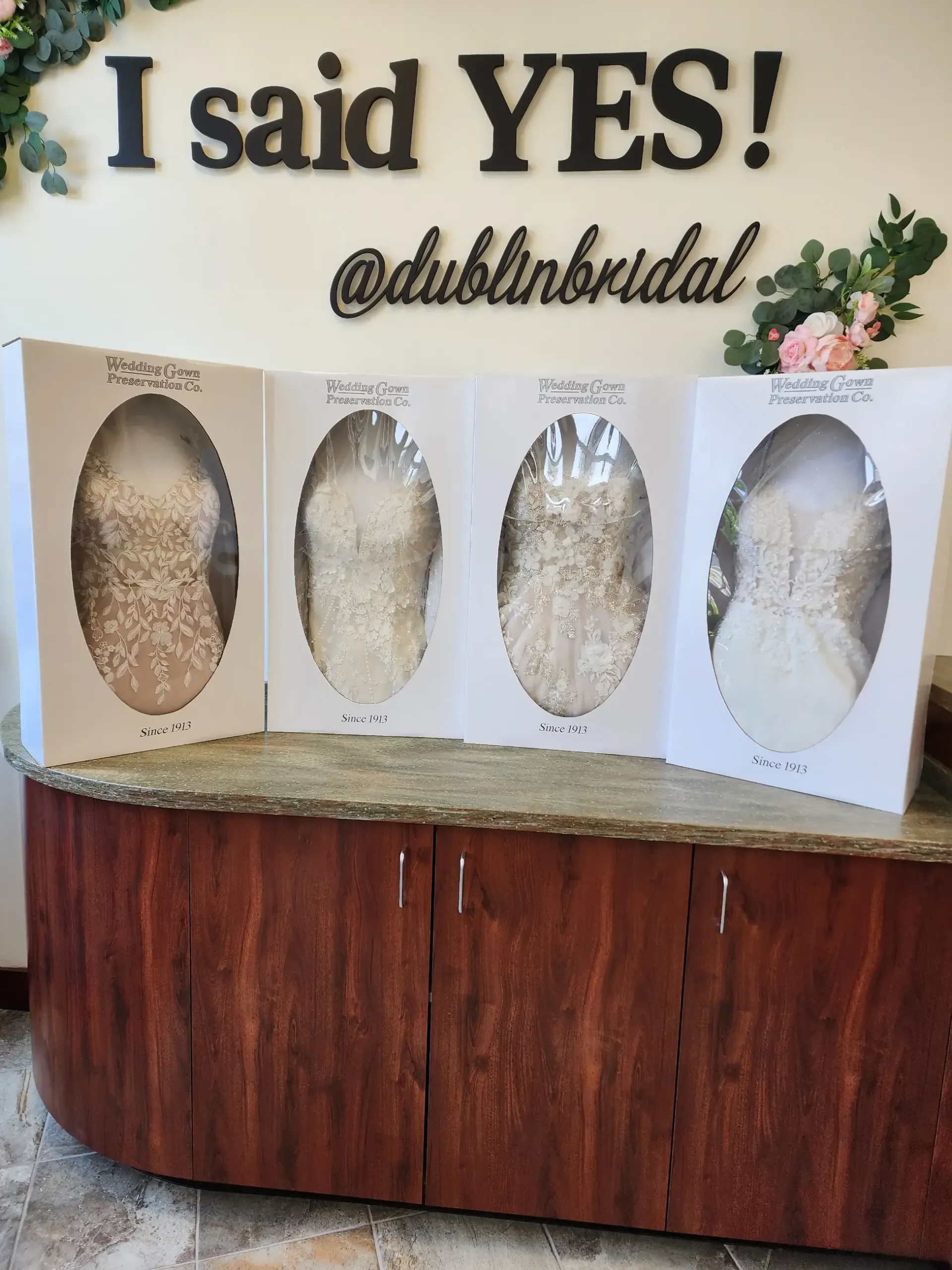 Four wedding dresses in boxes on a counter at Dublin Bridal, under a 