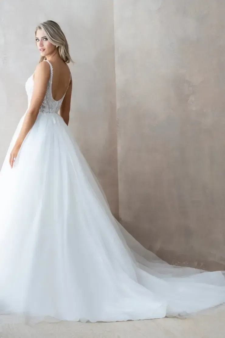 Woman in a white wedding gown, looking over her shoulder. The dress has a low back and long train.