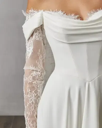 Back view of a bride wearing a white wedding dress with floral lace detailing and a long veil.