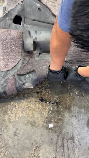 Person wearing black gloves, working on a floor, possibly repairing or cleaning.