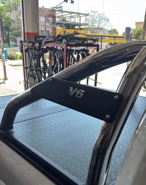 Spoiler trasero negro con el logotipo de YS montado en un vehículo en un taller, con portabicicletas al fondo.