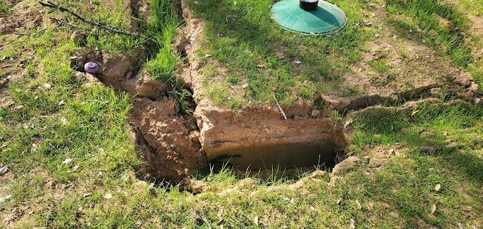 There is a hole in the ground in the grass.
