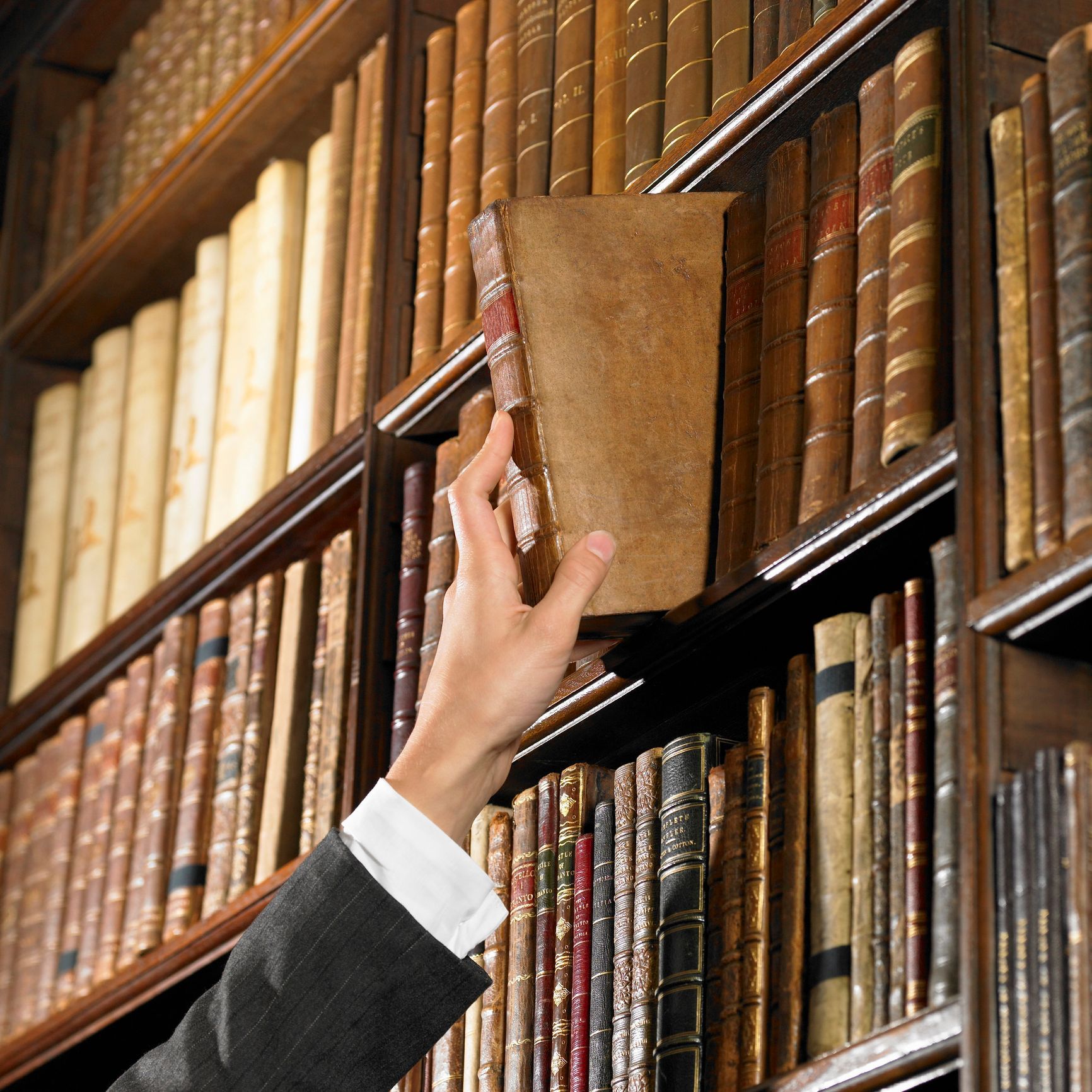 A person is reaching for a book in a library