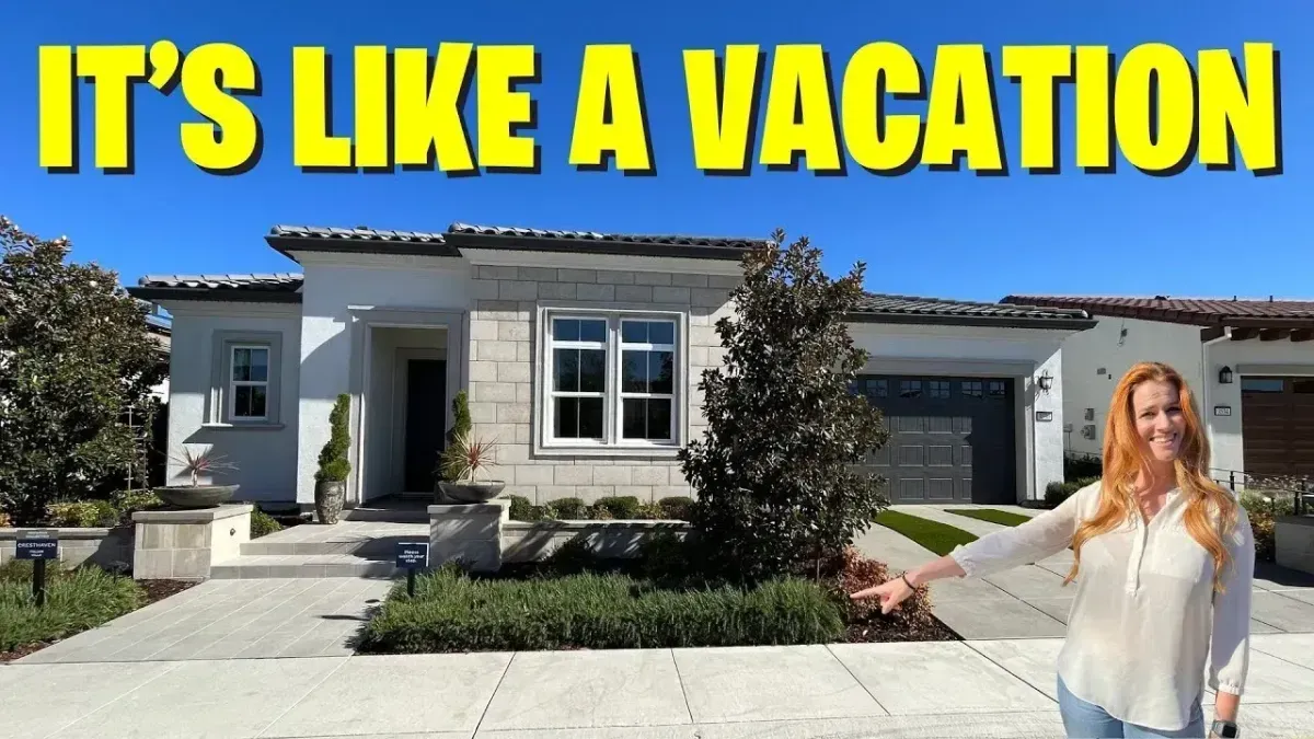 House with large yellow text “IT’S LIKE A VACATION” and a woman standing in the driveway.