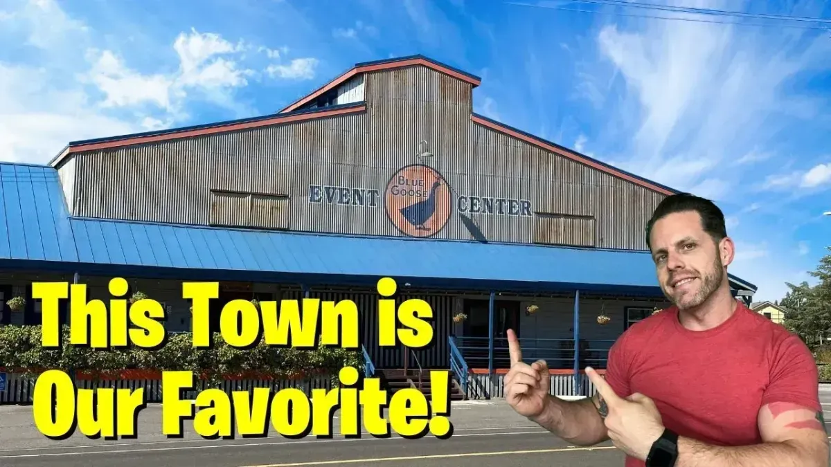 Man in red shirt pointing at a rustic building with text: “This Town is Our Favorite!”