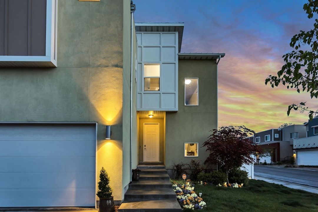 Modern house exterior at dusk with lit entryway, steps, and small landscaped front yard