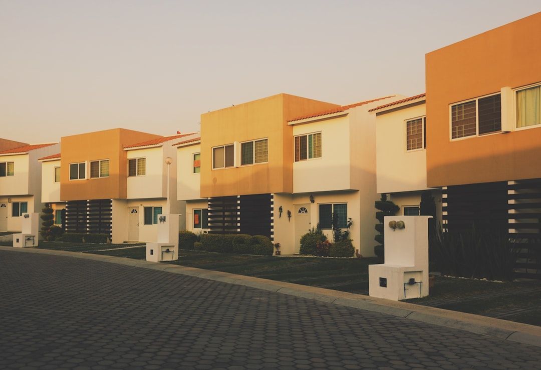 Row of modern orange-and-white townhouses along a paved street at sunset