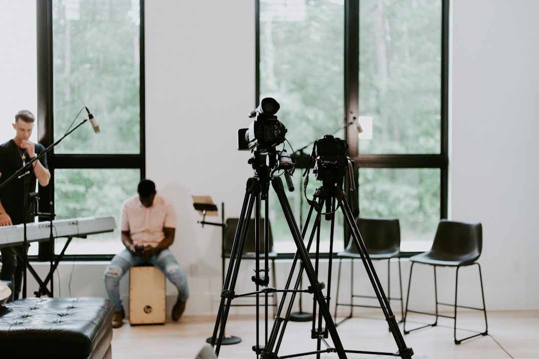 Music rehearsal in a bright studio with musicians, drums, keyboard, and camera tripods