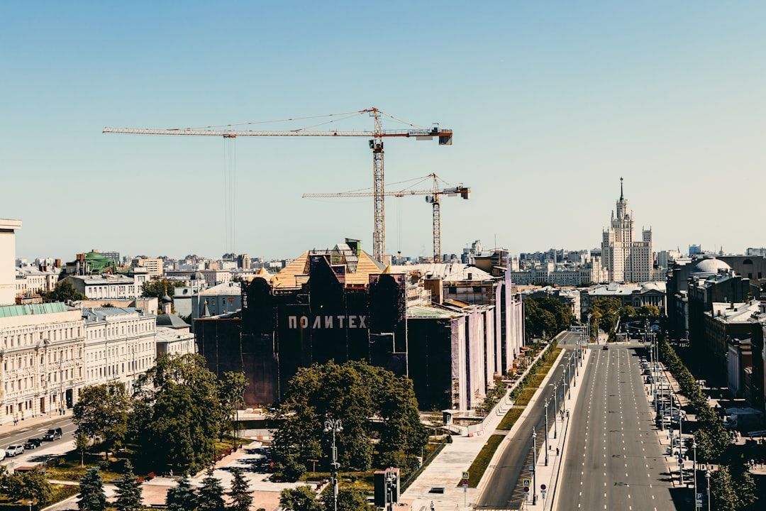 City street with construction cranes and a church skyline in the distance