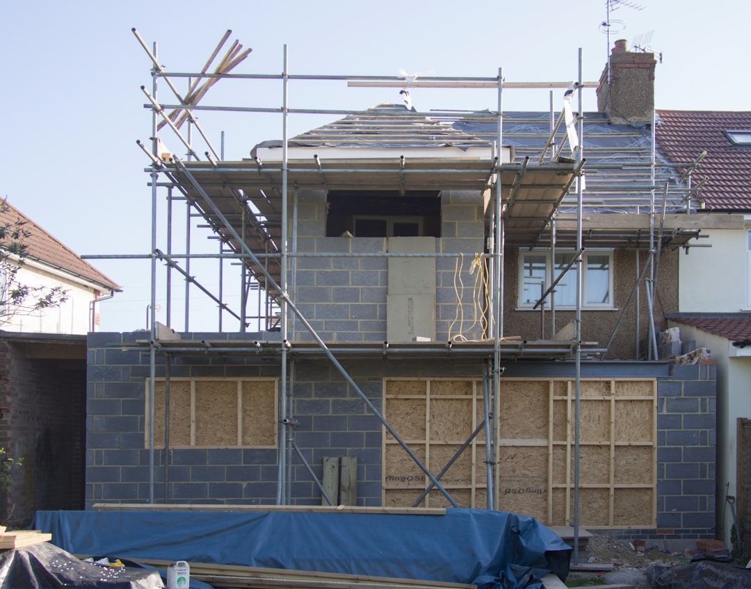House exterior under construction with scaffolding and boarded windows