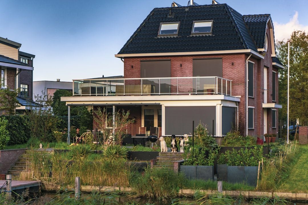 Modern brick house with a dark roof, large patio, and a garden in front