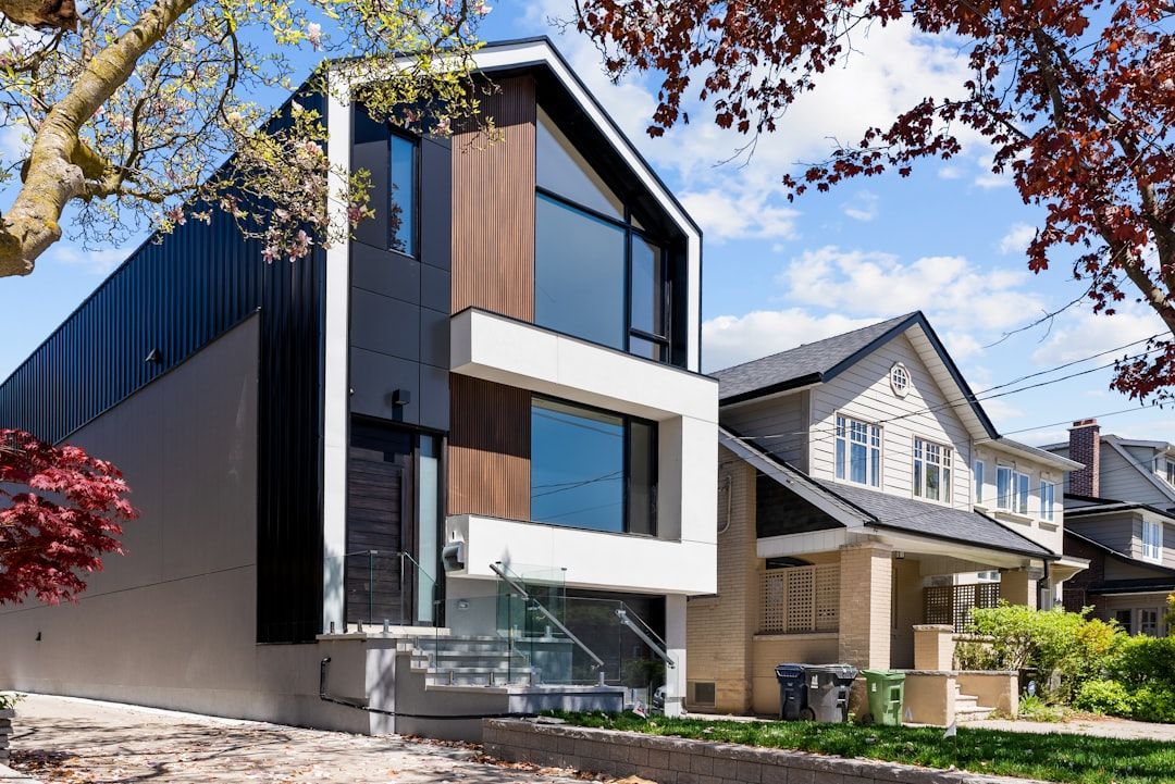 Modern two-story house with dark siding, white trim, and a small front yard on a suburban street