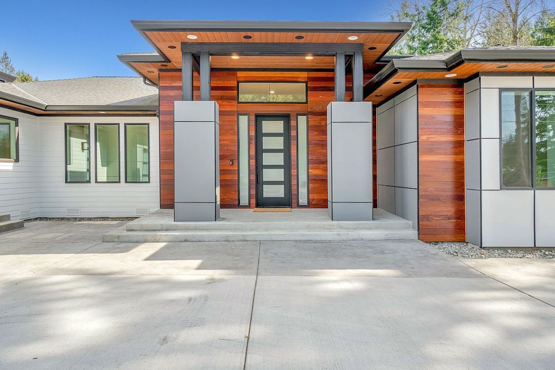 Modern home exterior with wood and gray accents, front entry, and a wide concrete driveway