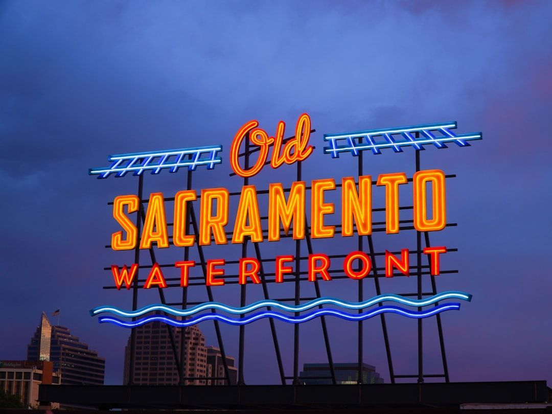 Neon “Old Sacramento Waterfront” sign glowing against a purple dusk sky