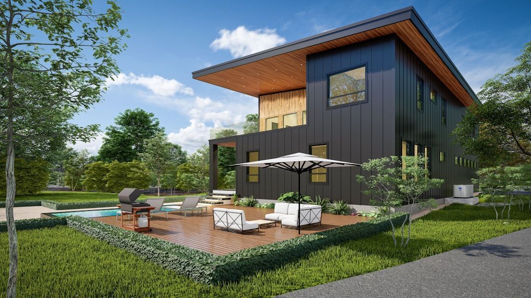 Modern two-story dark wood house with a patio, white outdoor furniture, and landscaped garden under a blue sky