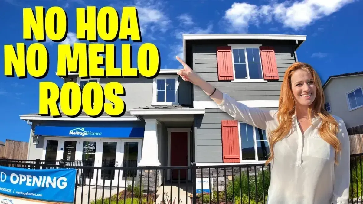 “No HOA, No Mello Roos” real estate sign in front of a house with a smiling woman standing nearby.