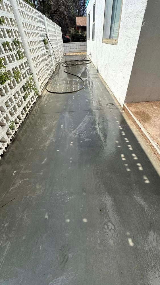 A concrete sidewalk is being cleaned with a pressure washer.