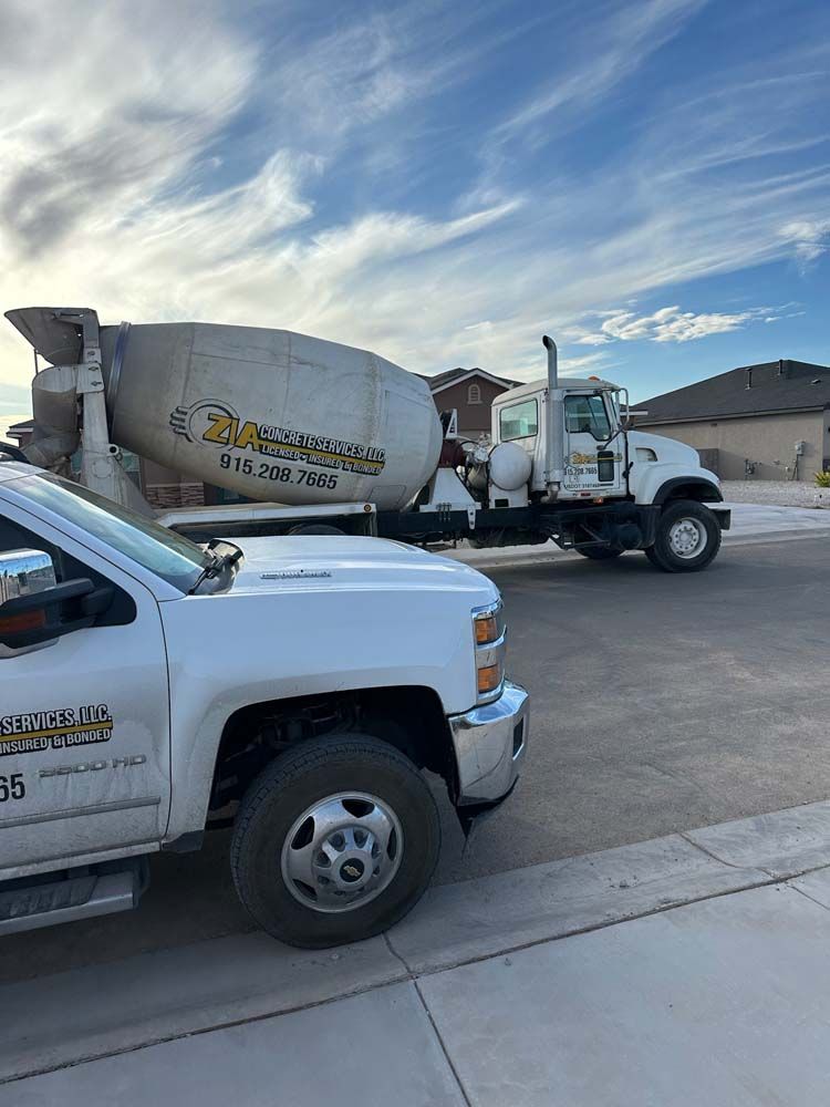 A white truck is parked next to a concrete mixer truck.