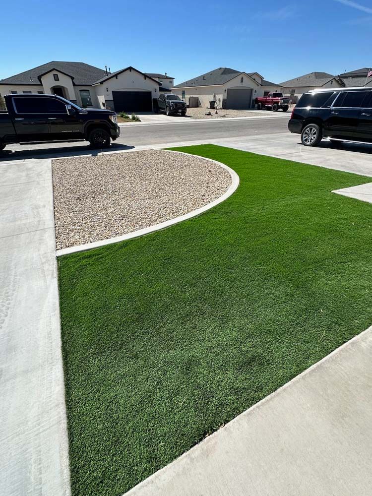 A black truck is parked in a driveway next to a lush green lawn.