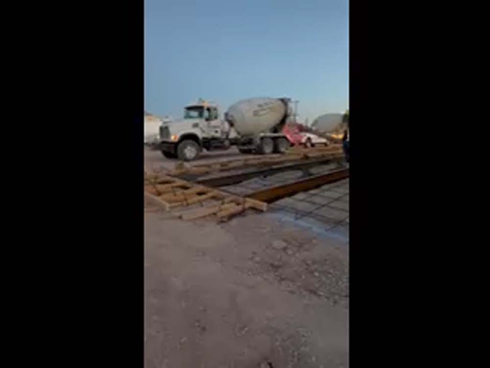 A concrete mixer truck is driving down a dirt road.