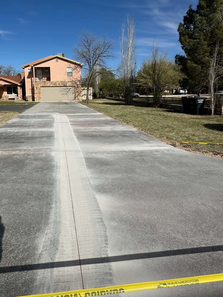 A concrete driveway with a house in the background.