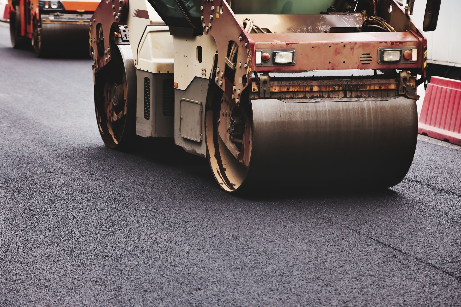Road roller compacting fresh asphalt during road construction work.